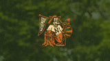 NativeMade 10 year raccoon mascot in an N sweater waving a NativeMade pennant beside a tree stump