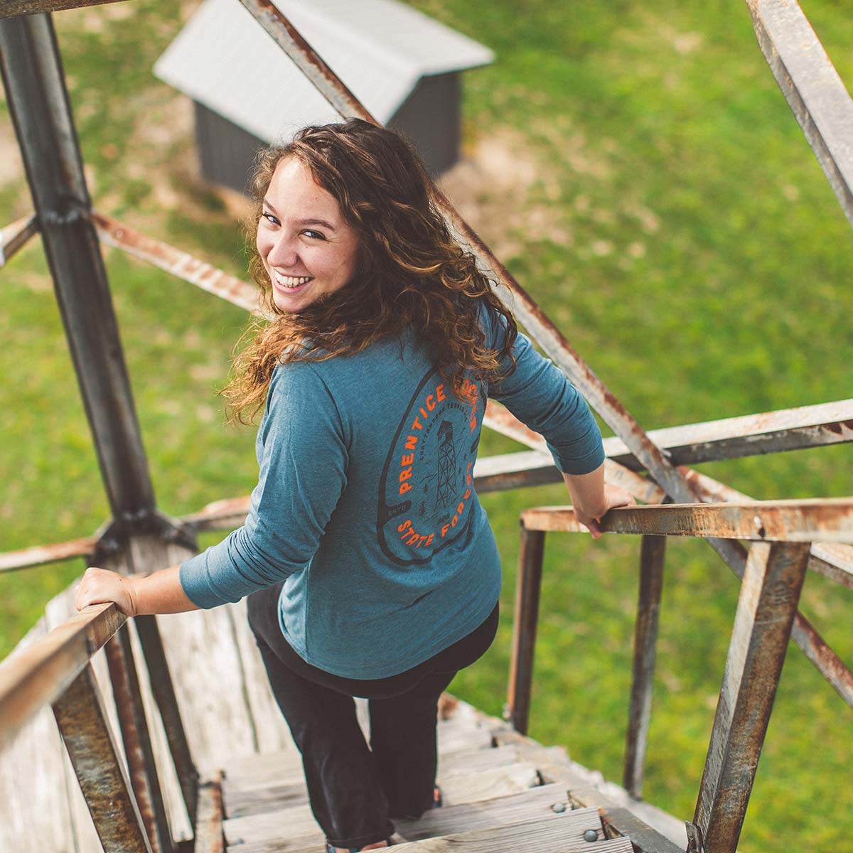 Model wearing Prentice Cooper State Forest long sleeve while climbing a watch tower