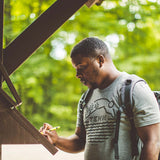 Hiker wearing Tenn Badge t-shirt in the woods at Prentice Cooper State Forest